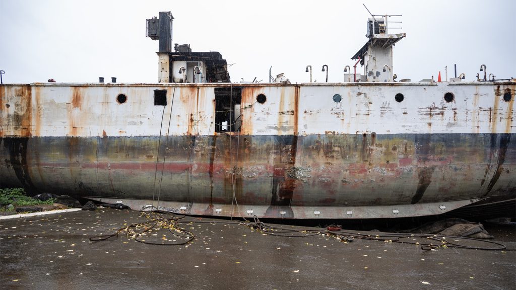 A half-broken apart ship lies beached on the shore at Deep Water Recovery's shipbreaking site in Union Bay